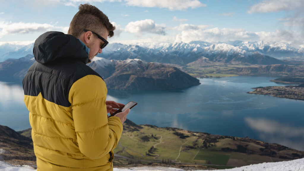 A hiker enjoys seamless SMS communication in a remote location, courtesy of SpaceX Starlink.